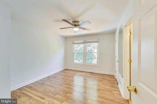 a view of a room with a ceiling fan and wooden floor