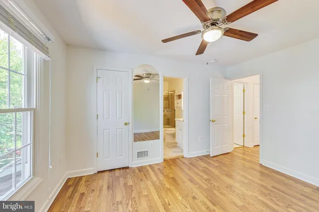 a view of empty room with wooden floor and fan