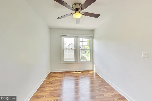 a view of an empty room with window and chandelier fan