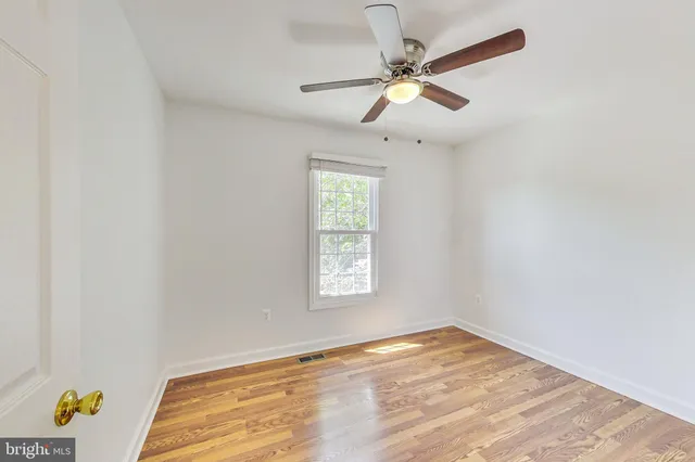 an empty room with a window and ceiling fan