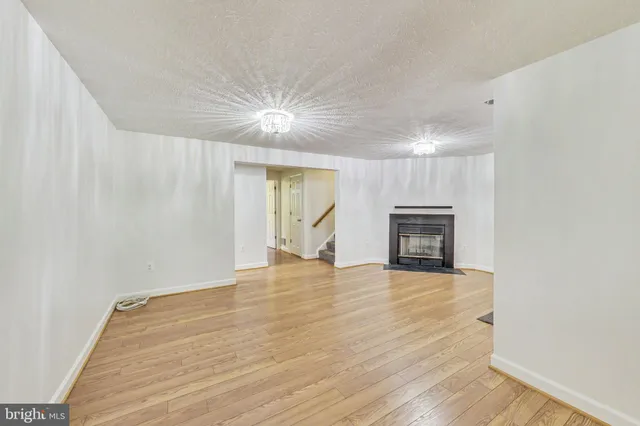 a view of empty room with wooden floor and fireplace