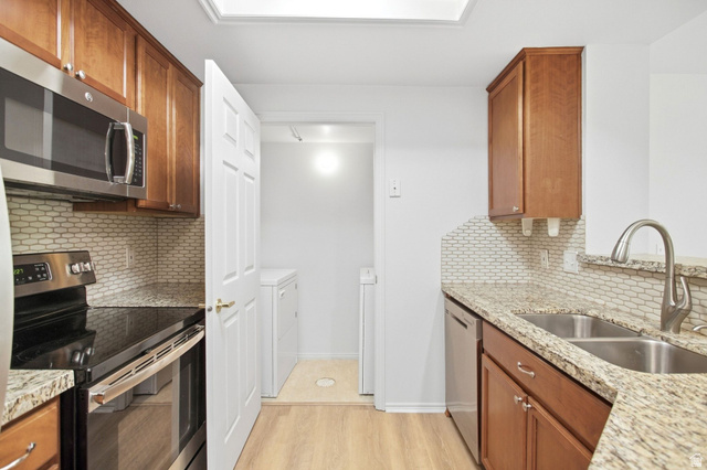 900 Bitner Road, Unit B14 Park City, UT 84098 - Photo 3 of 17 Kitchen featuring wood-finish cabinetry, light-toned granite countertops, and a full stainless steel appliance package including a built-in microwave, range, and dishwasher