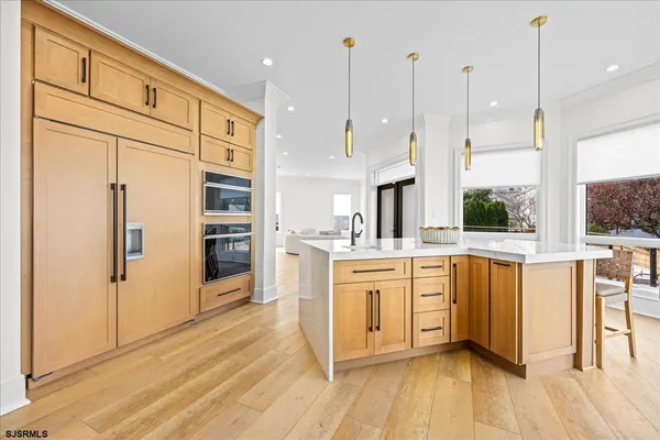 a open kitchen with stainless steel appliances granite countertop a refrigerator a oven a sink with wooden floors and cabinets