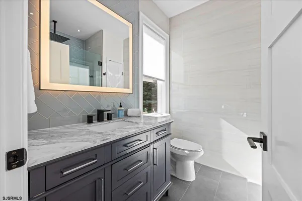 a bathroom with a granite countertop sink a toilet and a window