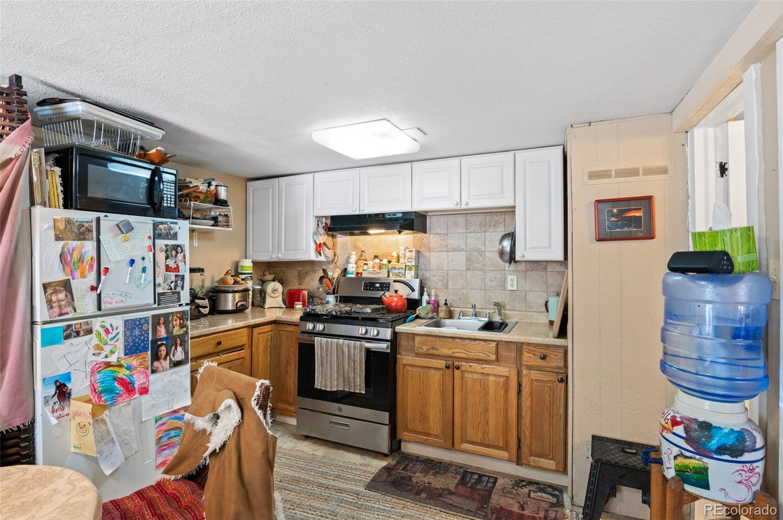4997 Camel Heights Road Evergreen, CO 80439 - Photo 19 of 24 a kitchen with stainless steel appliances a sink a stove a refrigerator cabinets and a dining table