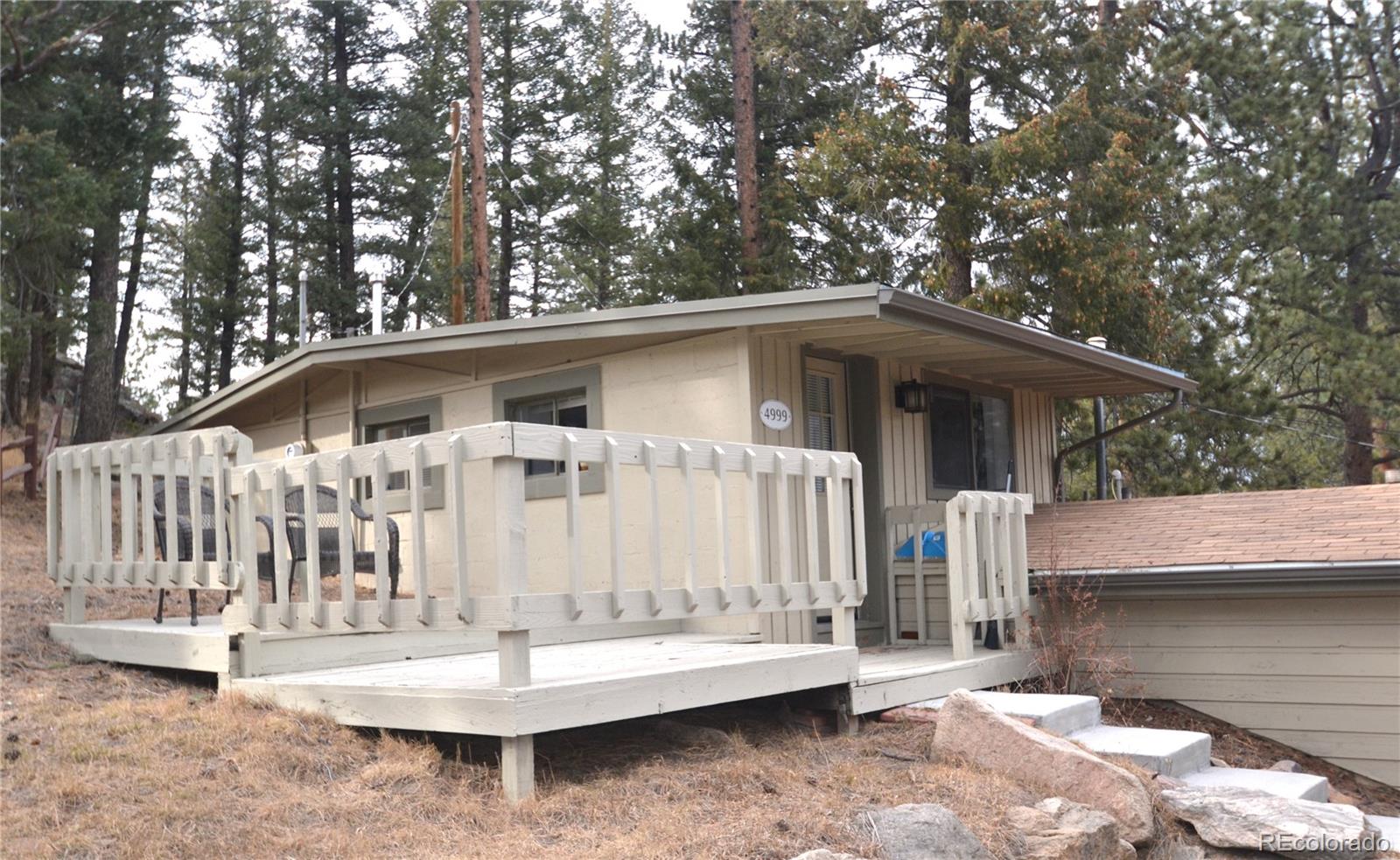 4997 Camel Heights Road Evergreen, CO 80439 - Photo 2 of 24 a white house with large trees and wooden fence