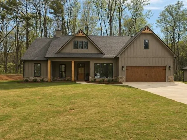 a front view of a house with a garden and tree