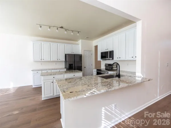 a kitchen with kitchen island granite countertop stainless steel appliances microwave stove refrigerator and cabinets