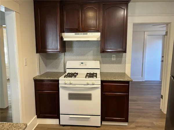 a kitchen with a stove top oven cabinets and a wooden floor