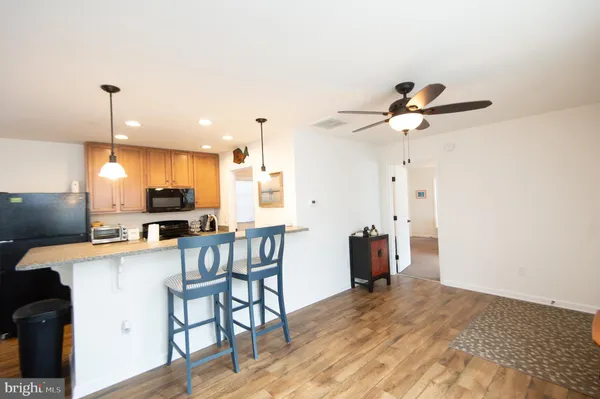 a kitchen with stainless steel appliances kitchen island granite countertop a table chairs and a refrigerator