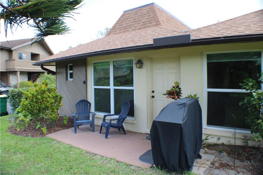 809 Palm View Drive, Unit 8 Naples, FL 34110 - Photo 26 of 26 a front view of a house with a yard glass top table and chairs