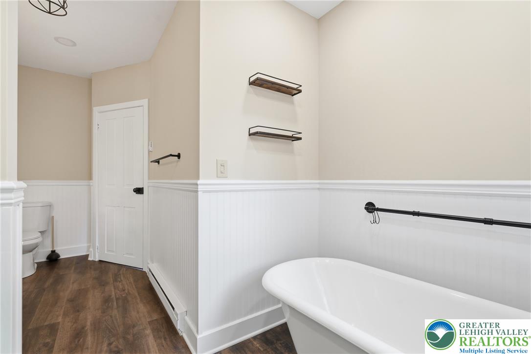 4682 Steuben Road Bethlehem, PA 18020 - Photo 37 of 79 A well-appointed bathroom features wood-look flooring and wainscoting, offering a clean, inviting aesthetic.
