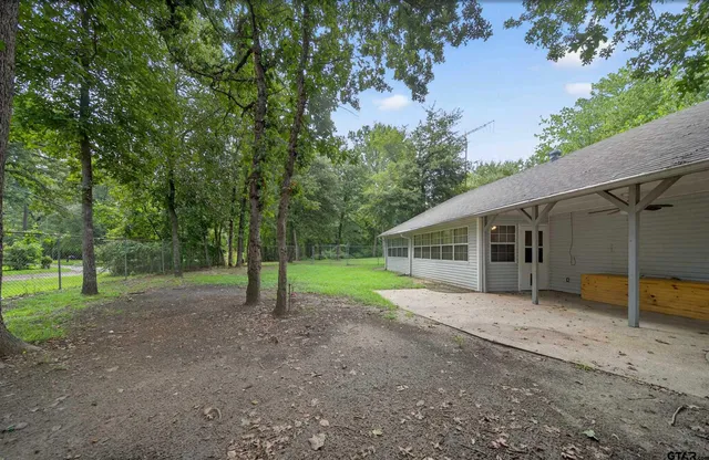 a view of a house with large trees and a forest