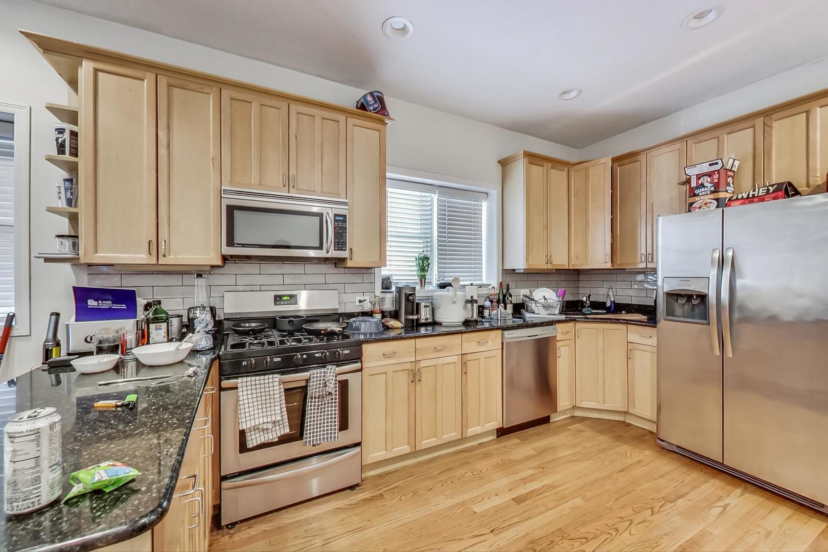1119 West Addison Street Chicago, IL 60613 - Photo 7 of 36 a kitchen with stainless steel appliances granite countertop a stove a sink and a refrigerator