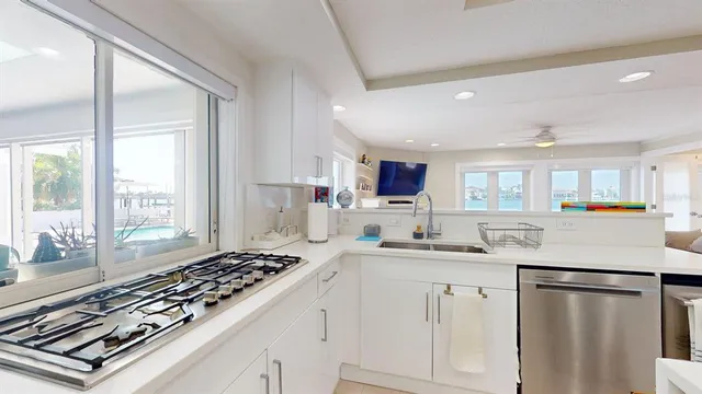 a kitchen with stainless steel appliances a refrigerator a stove a sink a oven with white cabinets and wooden floor