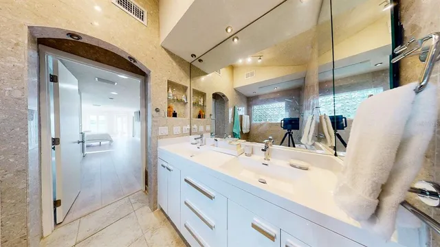 a bathroom with a sink and mirror with bathtub