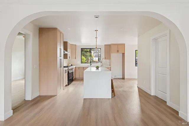 a view of kitchen with stainless steel appliances refrigerator stove and wooden floor