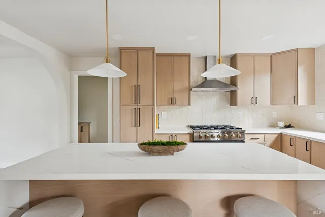 a kitchen with stainless steel appliances granite countertop a stove a sink a refrigerator white cabinets and wooden floor