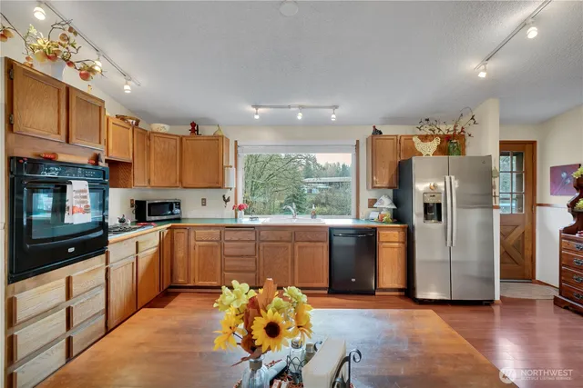 a kitchen with stainless steel appliances granite countertop a refrigerator a sink dishwasher a stove and white cabinets with wooden floor