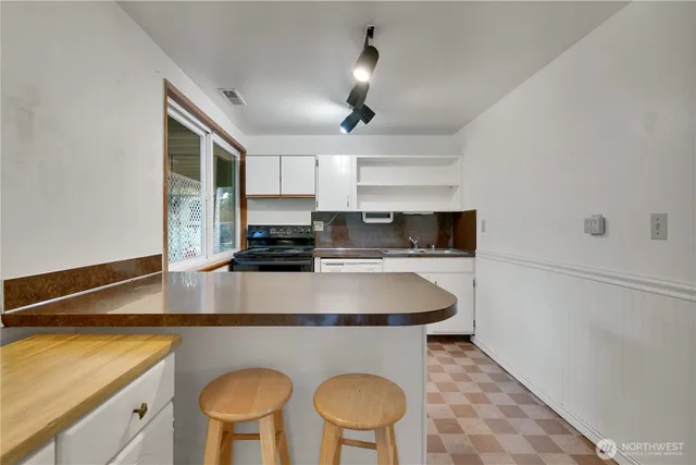 a kitchen with stainless steel appliances granite countertop a sink a stove a refrigerator a microwave oven with white cabinets and wooden floor