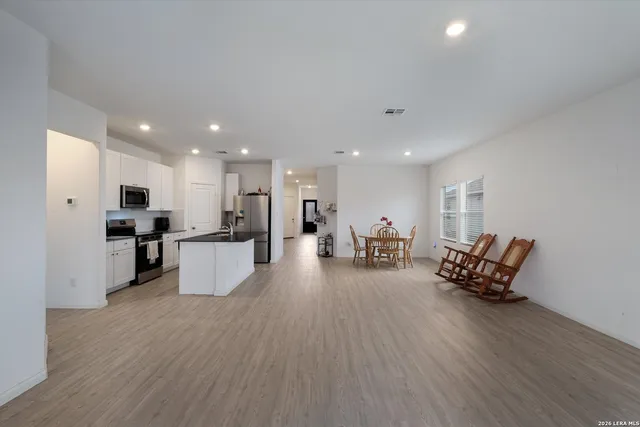 a living room with furniture and kitchen view with wooden floor