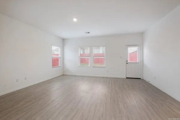 an empty room with wooden floor and windows