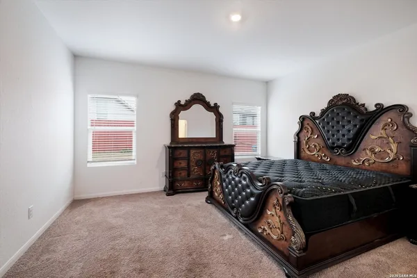 a bedroom with a bed a dresser and windows