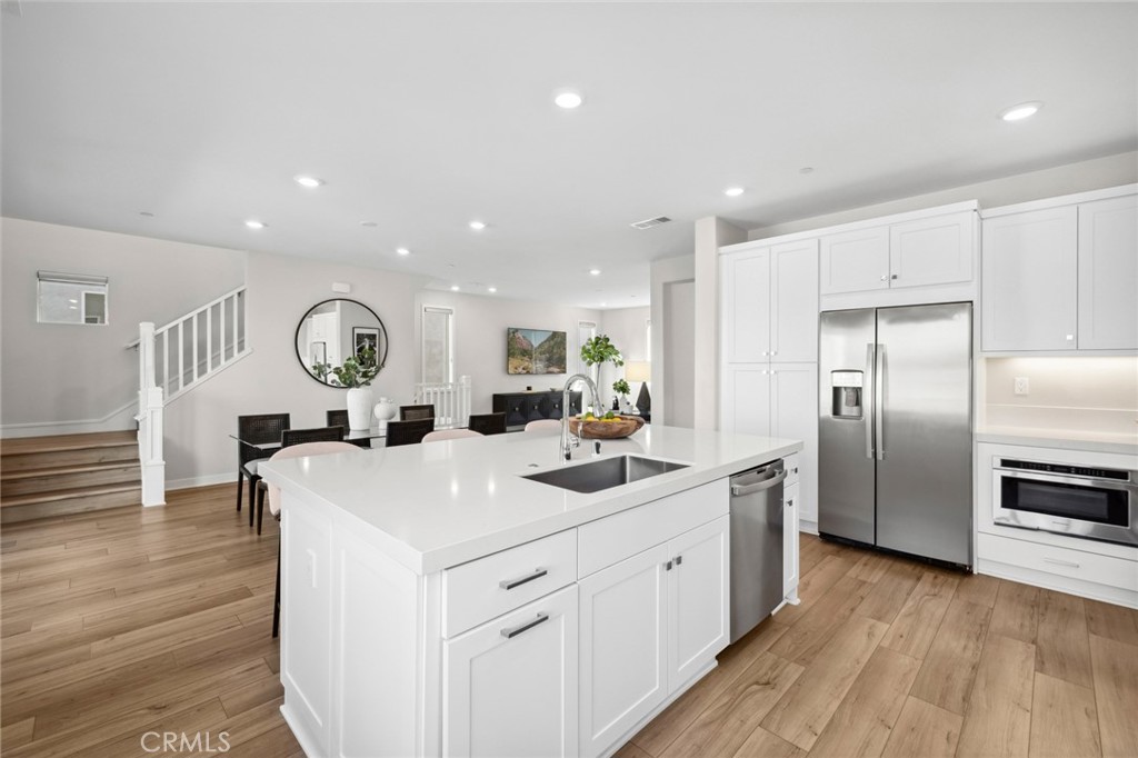 526 Serrano Summit Drive Lake Forest, CA 92630 - Photo 9 of 59 a kitchen with a sink dishwasher a refrigerator and a dining table with wooden floor