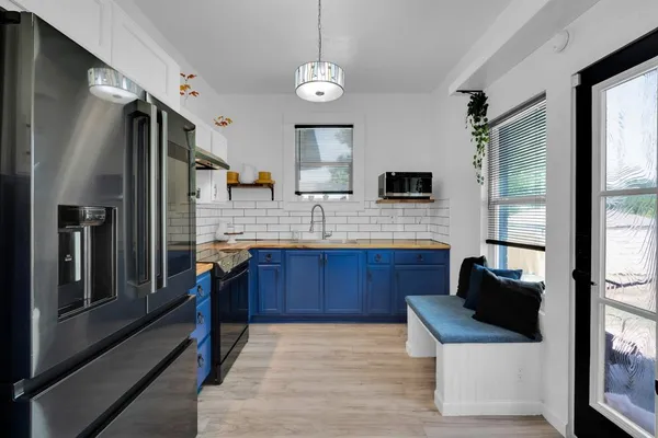 a kitchen with stainless steel appliances granite countertop a refrigerator a sink dishwasher a stove and a refrigerator with wooden floor
