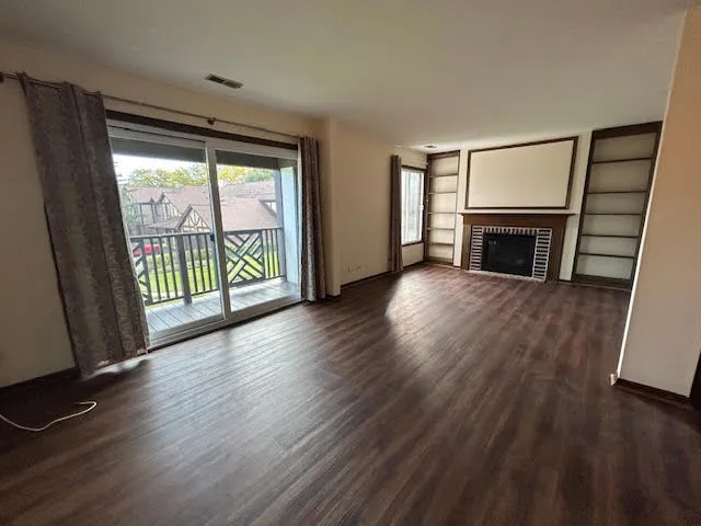 an empty room with wooden floor fireplace and windows