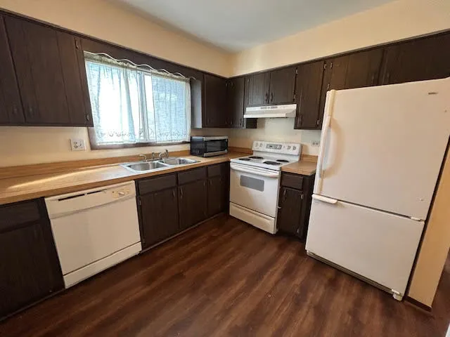 a kitchen with a sink a refrigerator a microwave and cabinets