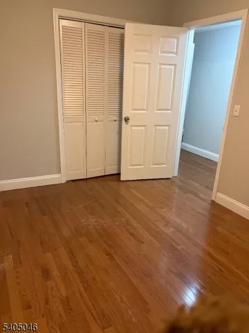 a view of an empty room with wooden floor and closet