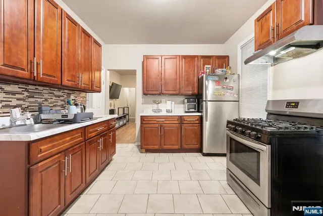 a kitchen with stainless steel appliances granite countertop a stove top oven a sink dishwasher and a refrigerator