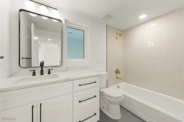 a bathroom with a double vanity sink toilet mirror and bathtub
