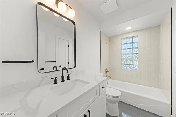 a bathroom with a bathtub shower sink vanity mirror and toilet