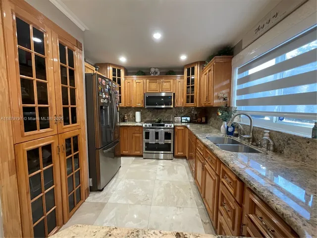 a kitchen with stainless steel appliances granite countertop a stove a sink and a refrigerator