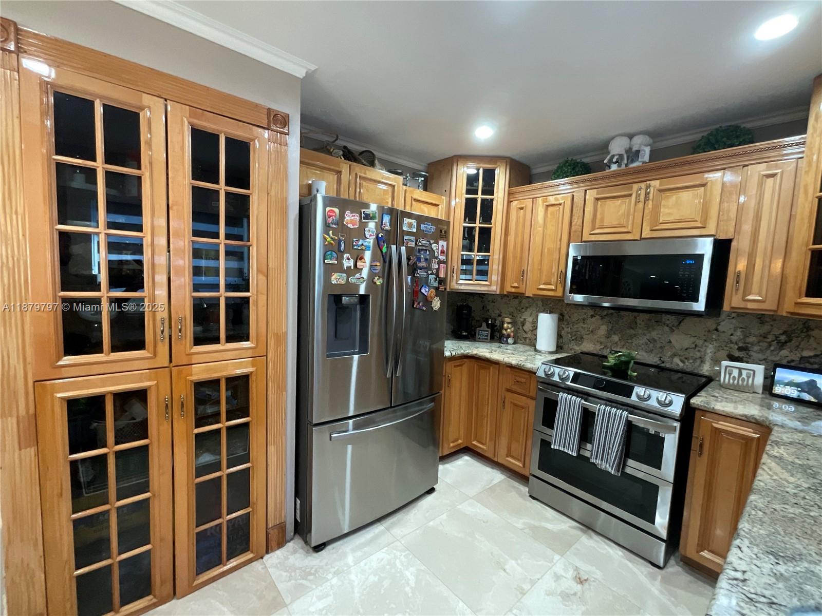 9710 Southwest 13th Street, Unit 9710 Pembroke Pines, FL 33025 - Photo 7 of 43 a kitchen with stainless steel appliances granite countertop a refrigerator and a sink