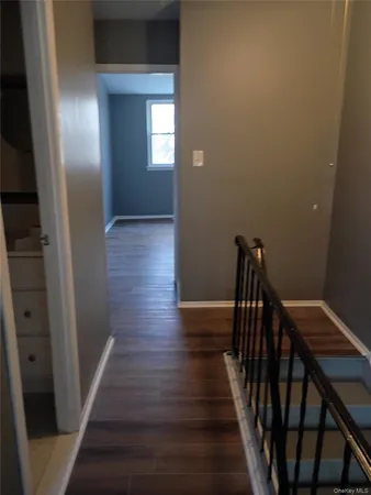 a view of a hallway with wooden floor and stairs