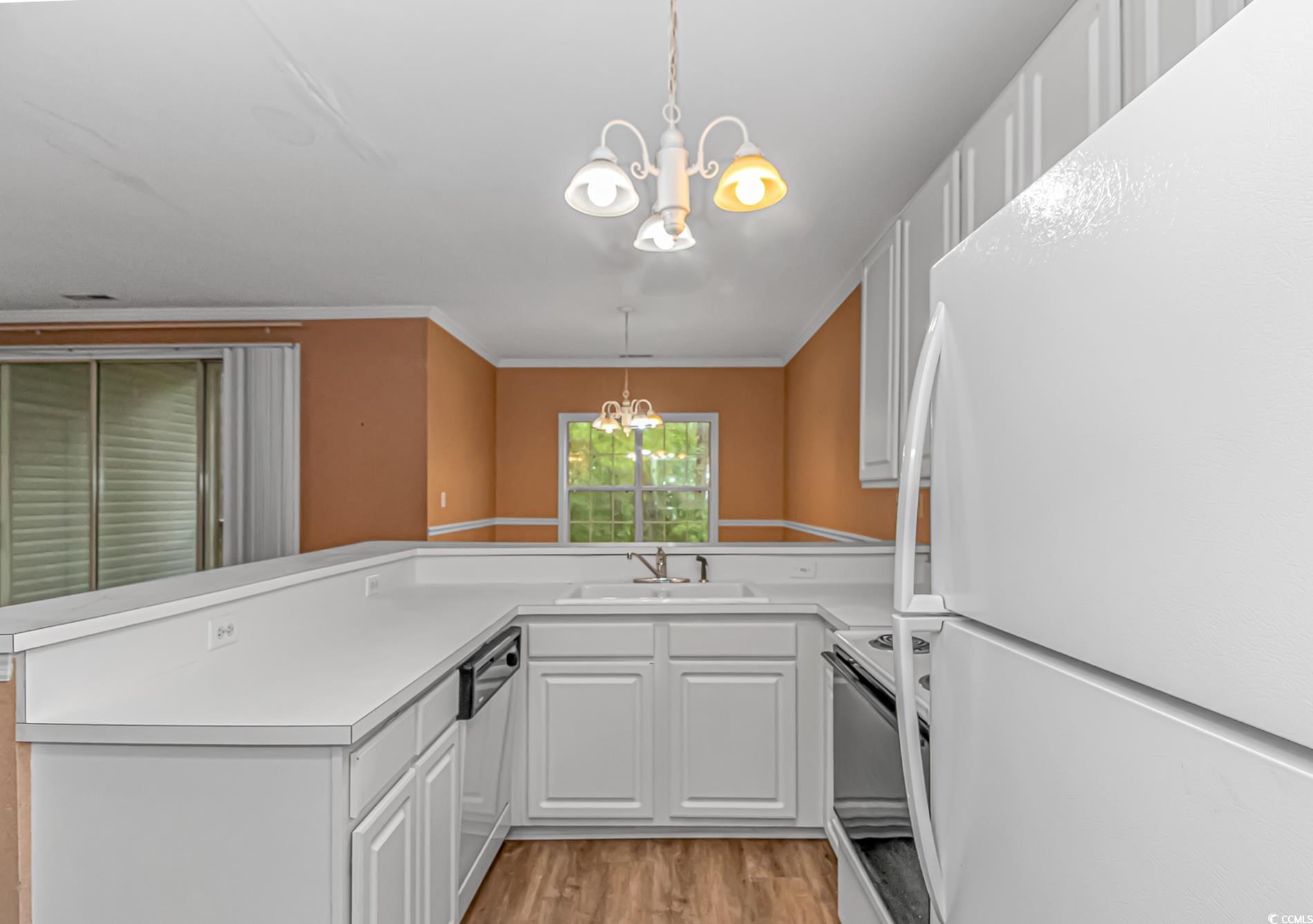 4814 Innisbrook Court, Unit 407 Myrtle Beach, SC 29579 - Photo 12 of 31 Kitchen with white appliances, a chandelier, pendant lighting, light countertops, and light wood-style floors