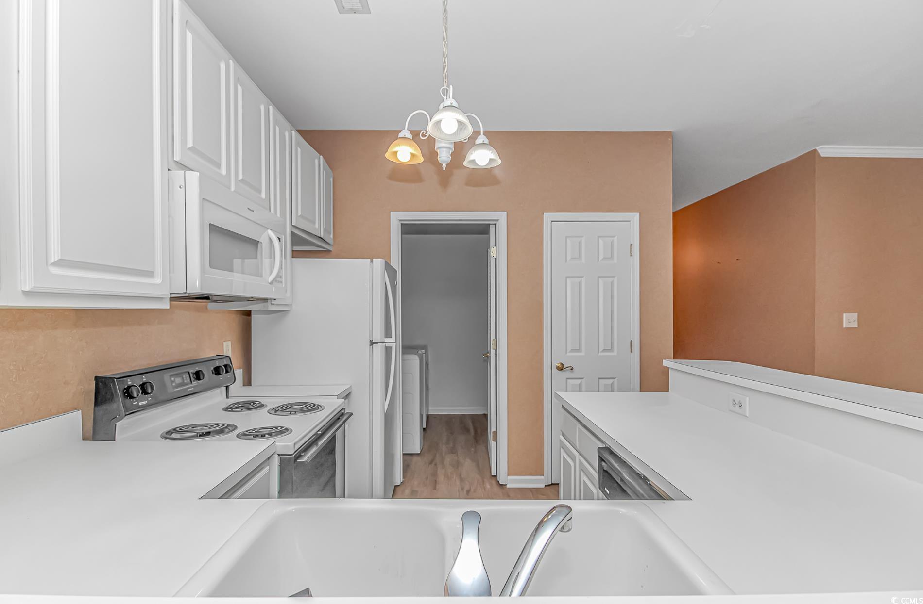 4814 Innisbrook Court, Unit 407 Myrtle Beach, SC 29579 - Photo 9 of 31 Kitchen featuring white cabinetry, range with electric cooktop, pendant lighting, white microwave, and a chandelier