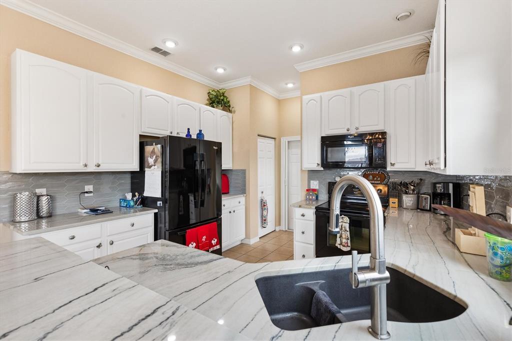 17031 Southeast 115th Terrace Road Summerfield, FL 34491 - Photo 12 of 54 a kitchen with stainless steel appliances kitchen island granite countertop a sink and a refrigerator