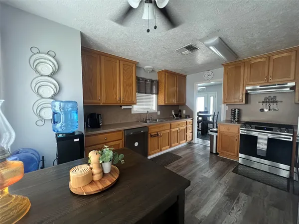 a kitchen with stainless steel appliances granite countertop a stove a sink dishwasher and cabinets with wooden floor