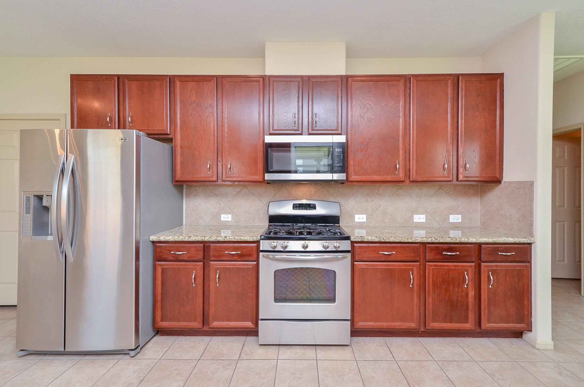 25135 Ginger Ranch Drive Katy, TX 77494 - Photo 7 of 32 The expansive kitchen features granite countertops, rich wood cabinetry, recessed lighting, and stainless steel appliances.