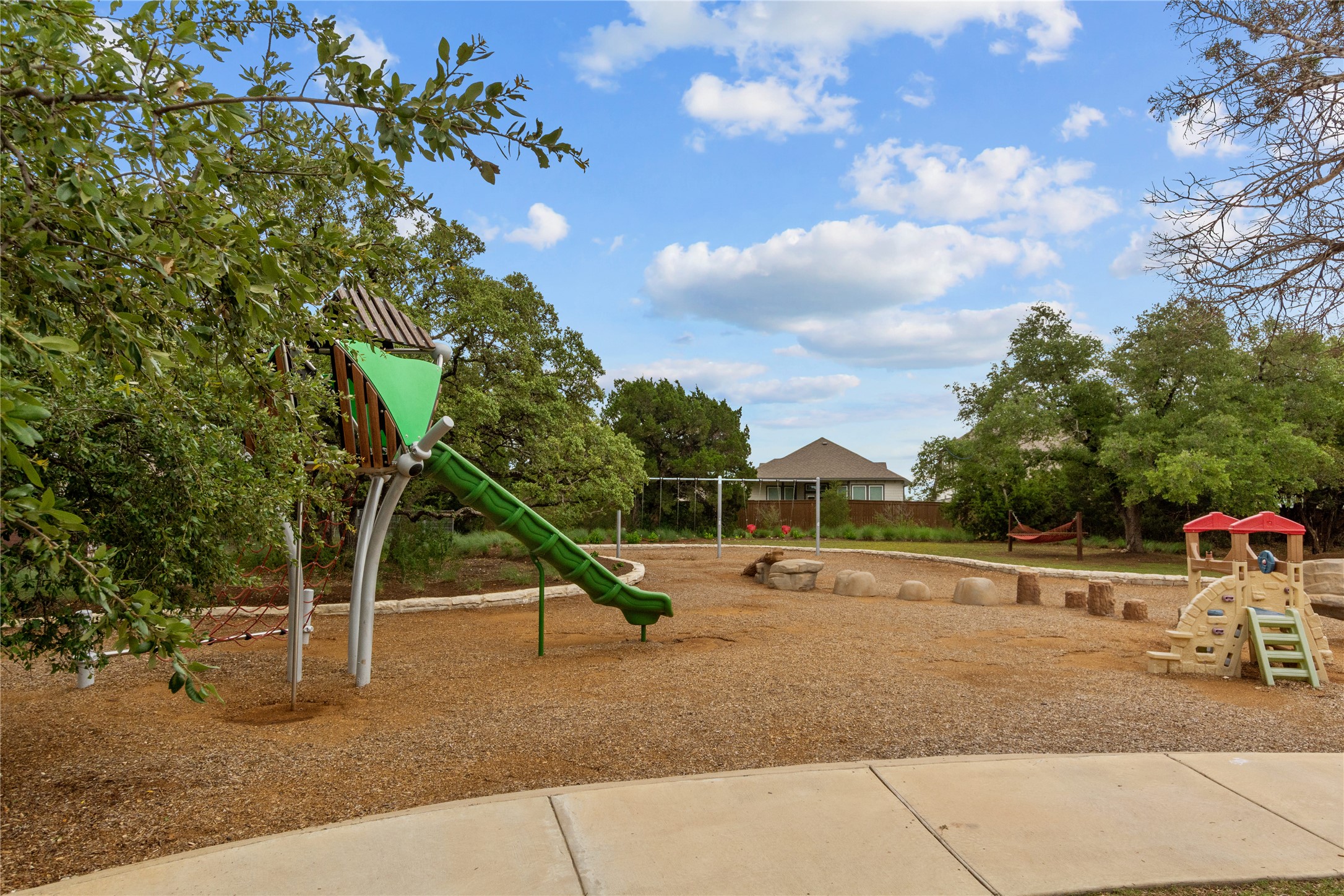 1108 Mallow Road Leander, TX 78641 - Photo 26 of 30 A spacious neighborhood playground is bordered by mature shade trees under a blue sky.