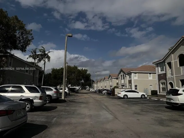 a view of road with card parked on side and retail shops