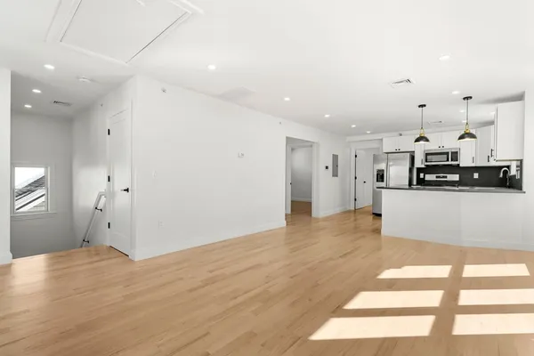 a view of a kitchen with refrigerator and wooden floor