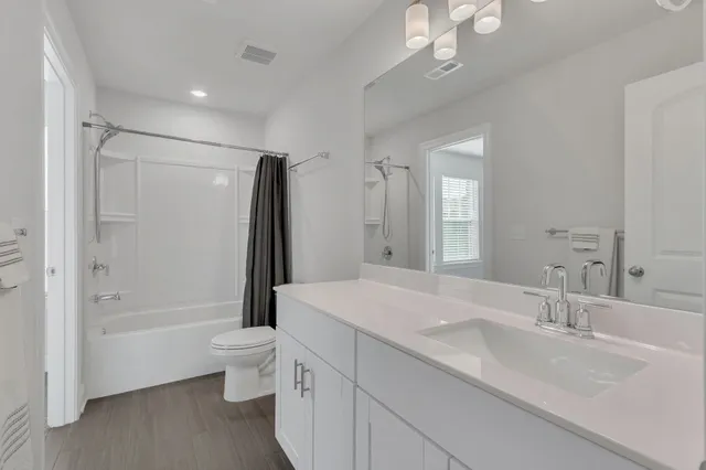 a bathroom with a double vanity sink toilet mirror and shower