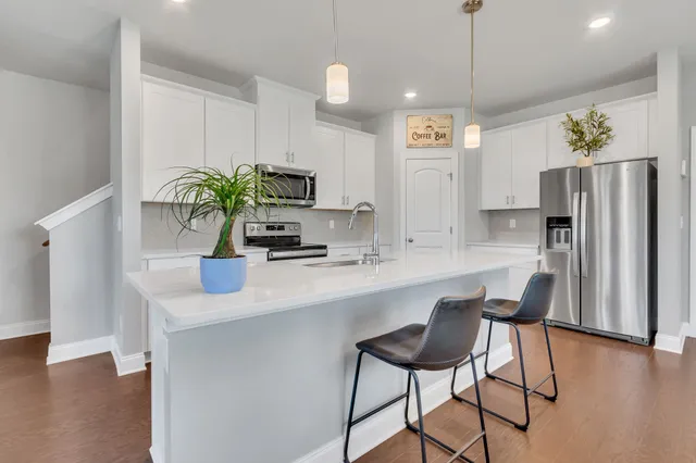 a kitchen with stainless steel appliances a dining table chairs refrigerator and sink