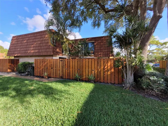 a view of a backyard with plants and large trees