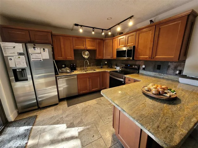 a kitchen with stainless steel appliances granite countertop a sink stove and refrigerator